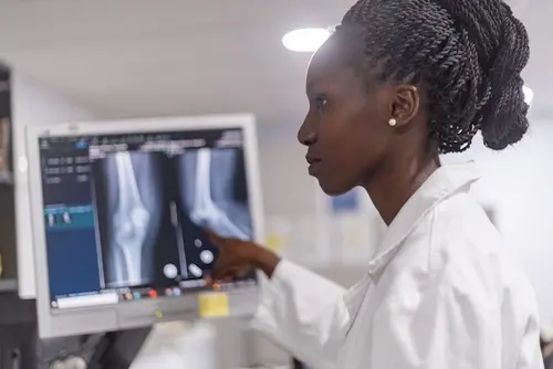 A doctor points to an x-ray of broken bones