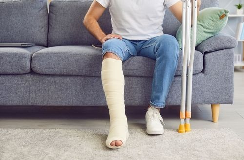 stages of bone healing, Bone Healing Timeline, Man With Broken Leg Sits On Sofa, bone fracture repair steps, fracture healing process, bone fracture healing timeline, broken bones healing time, how long does it take for a bone to heal, bone healing process, how long does it take for a fracture to heal, bone repair process, how long does bone healing take, xray stages of bone healing, broken bone timeline, Apex Orthopaedics Spine & Neurology explains the stages of bone healing and timeline in North Carolina.