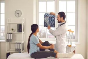 imaging tests after a car accident, doctor showing x-ray to patient with broken leg