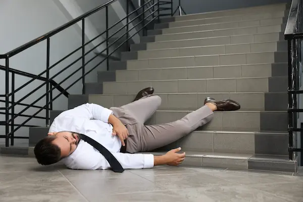 A person collapsed at the base of a set of stairs after suffering a premises liability accident.