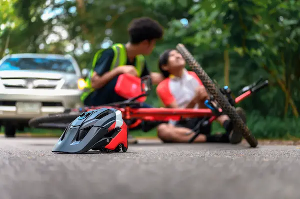 A cyclist collapses to the ground after an accident.