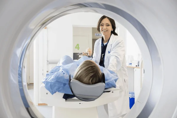 A patient slides into an MRI machine as a doctor looks on.